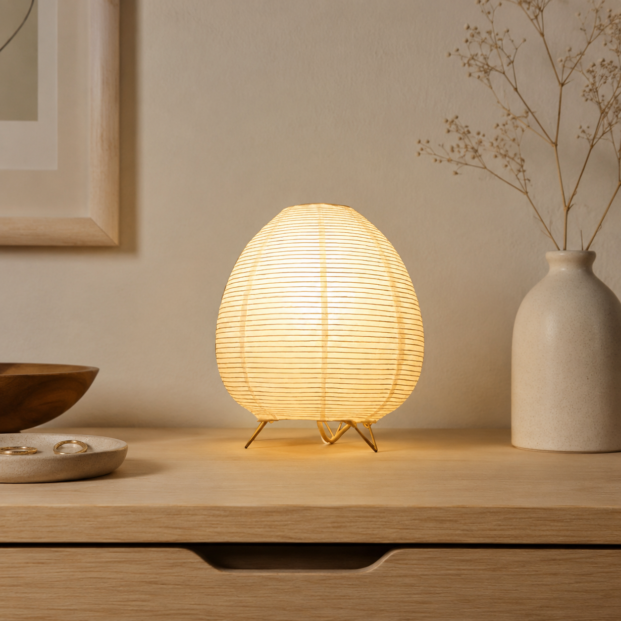 Egg-shaped lamp on a wooden surface with a vase and decor items in the background